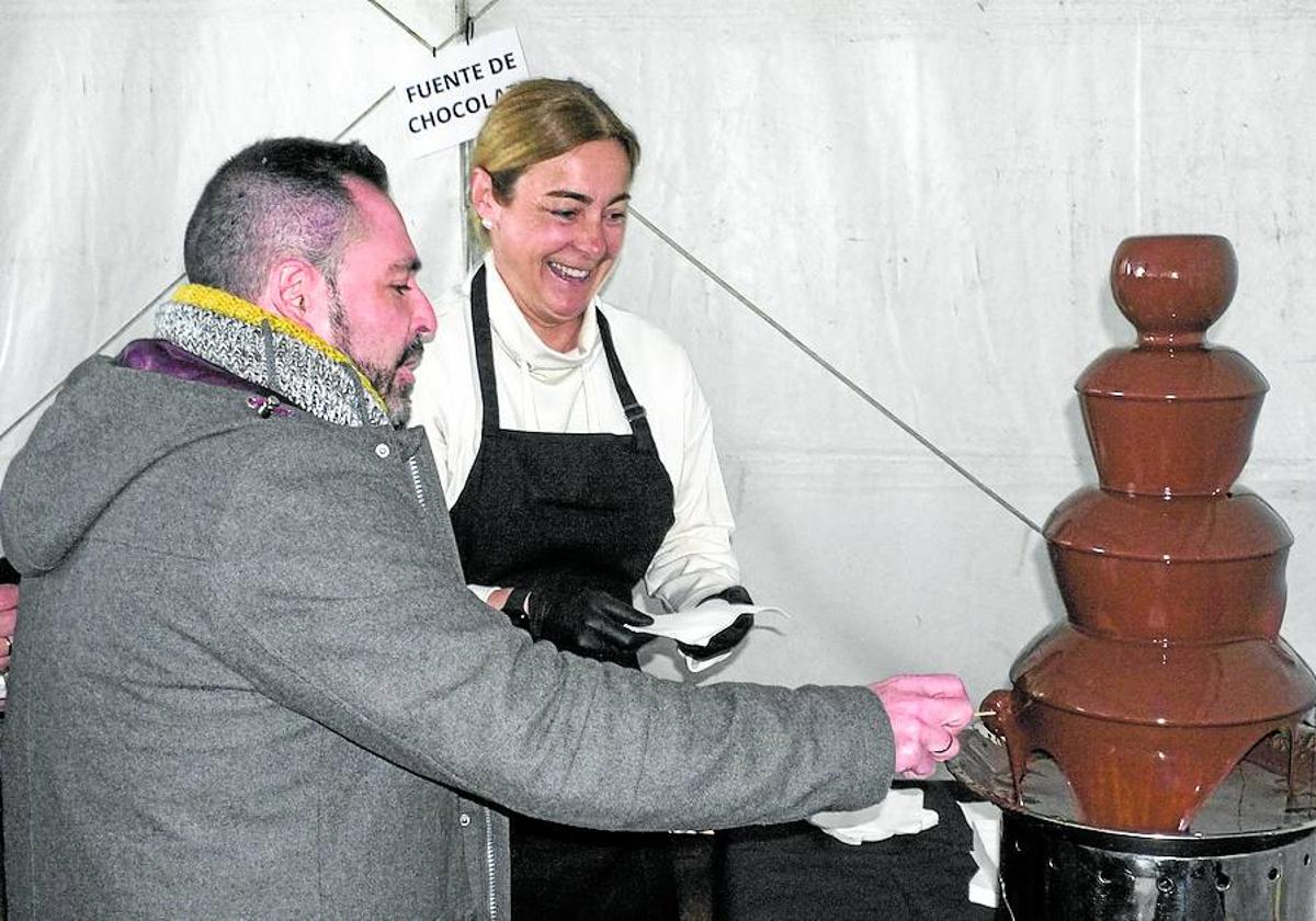 Un visitante disfruta de una fuente de chocolate instalada en uno de los puestos.