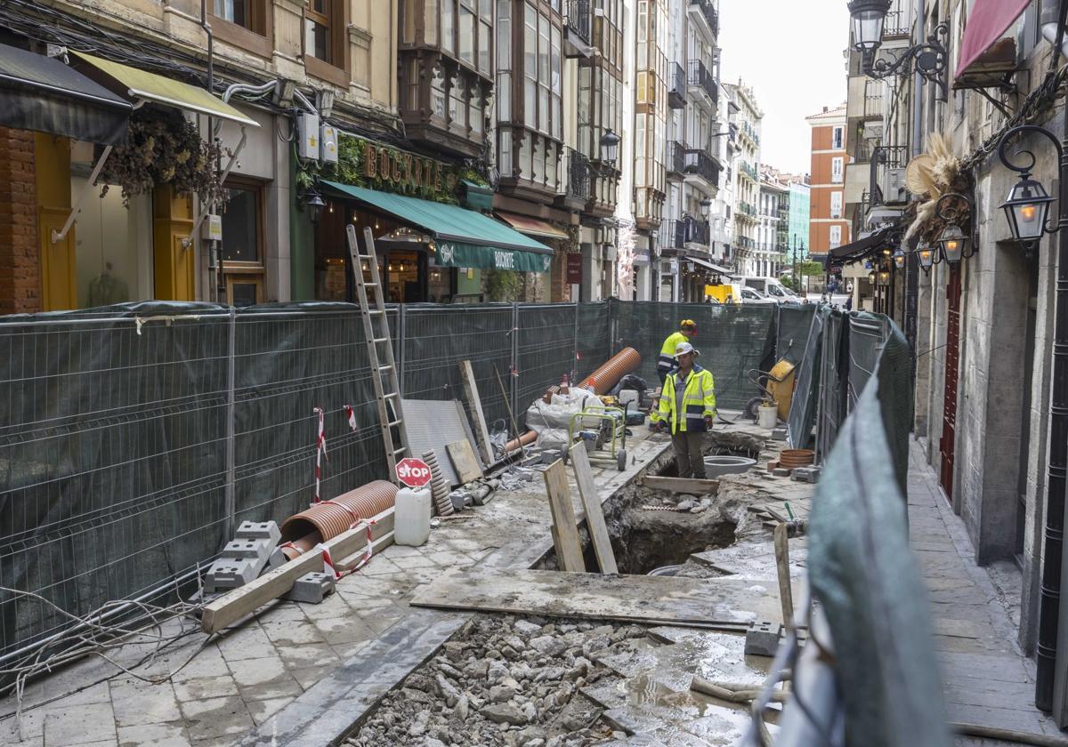 Operarios y maquinaria dentro del vallado de la santanderina calle del Medio.