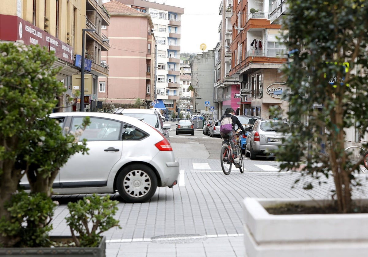 Un vehículo circula por la calle Julián Ceballos mientras un ciclista gira hacia la calle Alonso Astúlez, en Torrelavega.