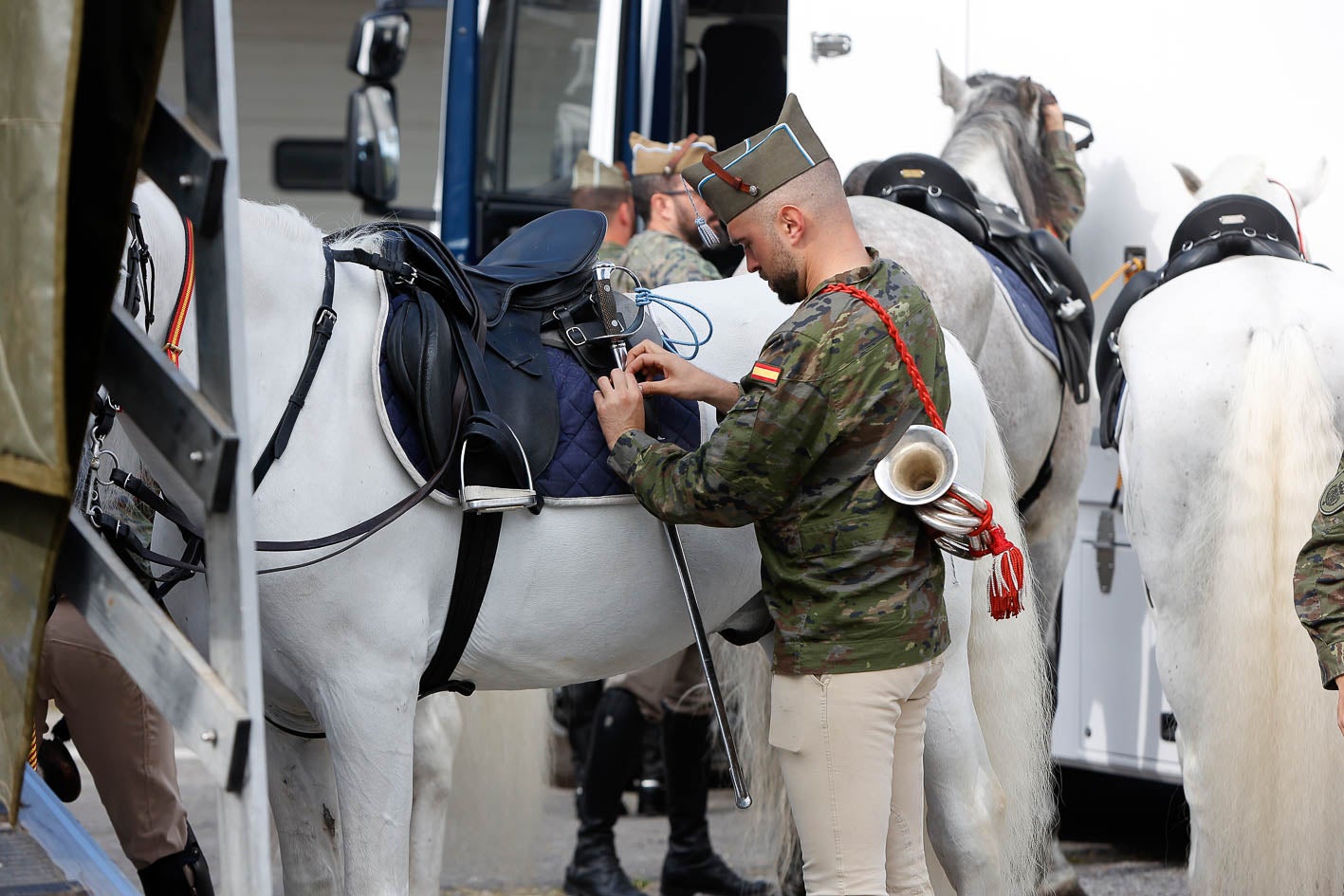 Un miembro de la banda de música prepara su caballo.