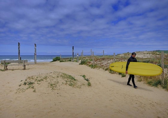 Un surfista abandona la playa de El Rosal, en San Vicente de la Barquera, en un día soleado.