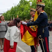 Una mujer besa la bandera de España que sujeta un Guardia Real.