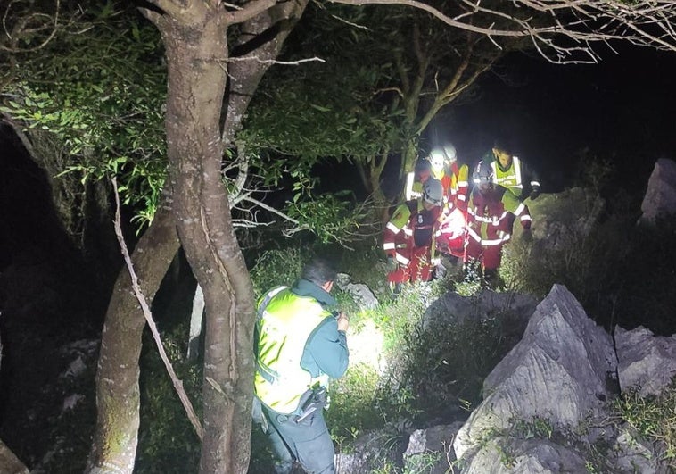 Efectivos de los servicios de emergencia porteando a Rafael en una zona de mucha vegetación y rocas.