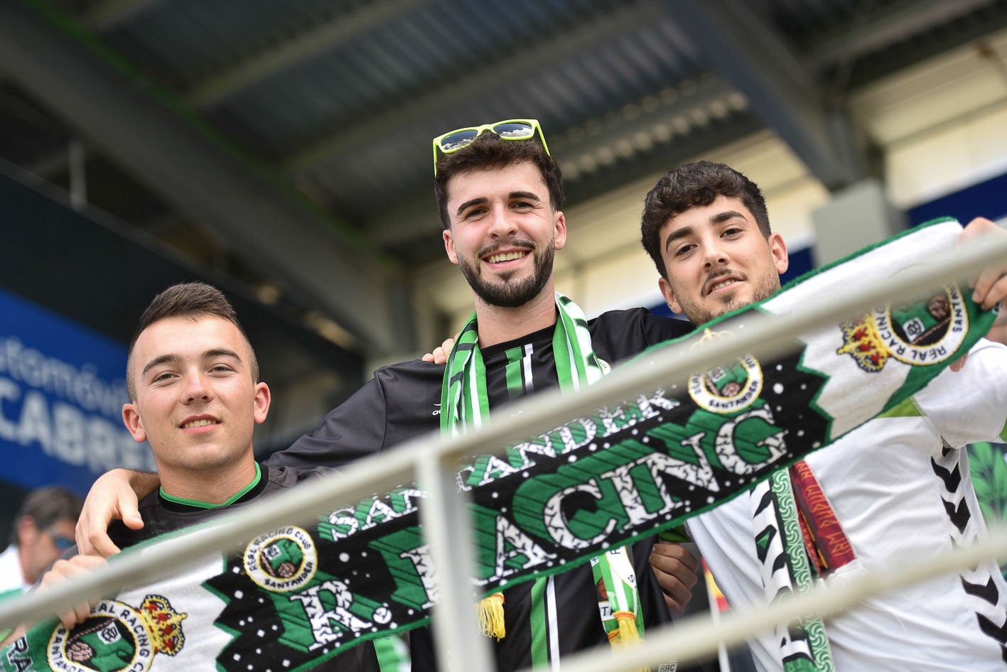 Tres racinguistas sostienen la bufanda del Racing en el estadio antes del partido. 