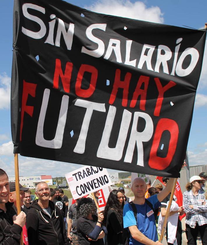 Imagen secundaria 2 - A la izquierda, los trabajadores concentrados en la puerta de la fábrica. A la derecha, una pancarta reivindicativa.