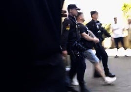 Uno de los detenidos, escoltado por los agentes al furgón de la Policía.