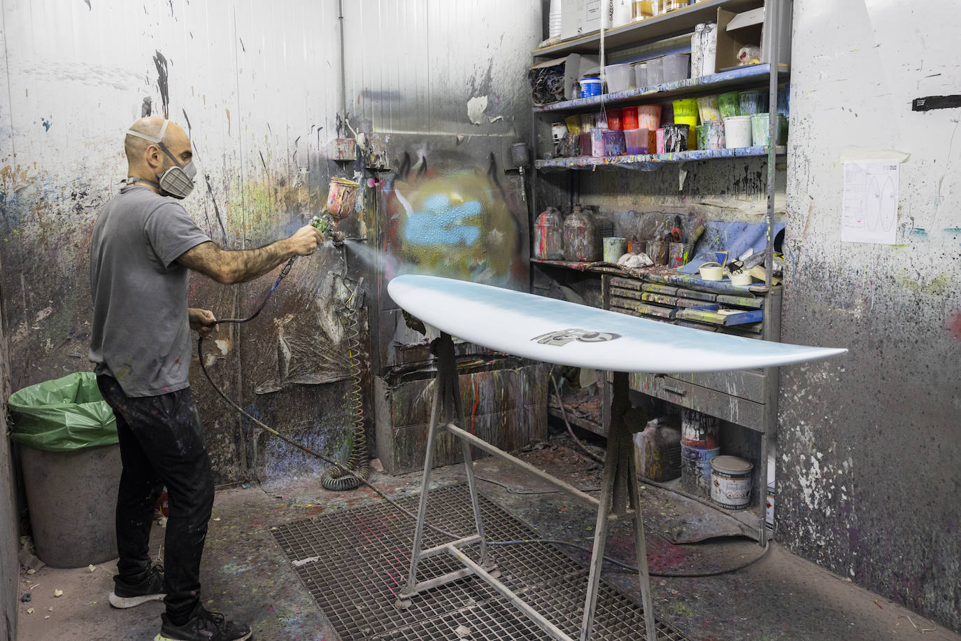 Shaper dando capa de pintura azul a una tabla.