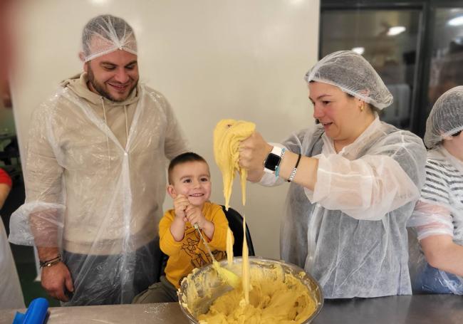 El pequeño Mauro, junto a sus padres, Adrián y Sara, colaborando en la elaboración del sobao.
