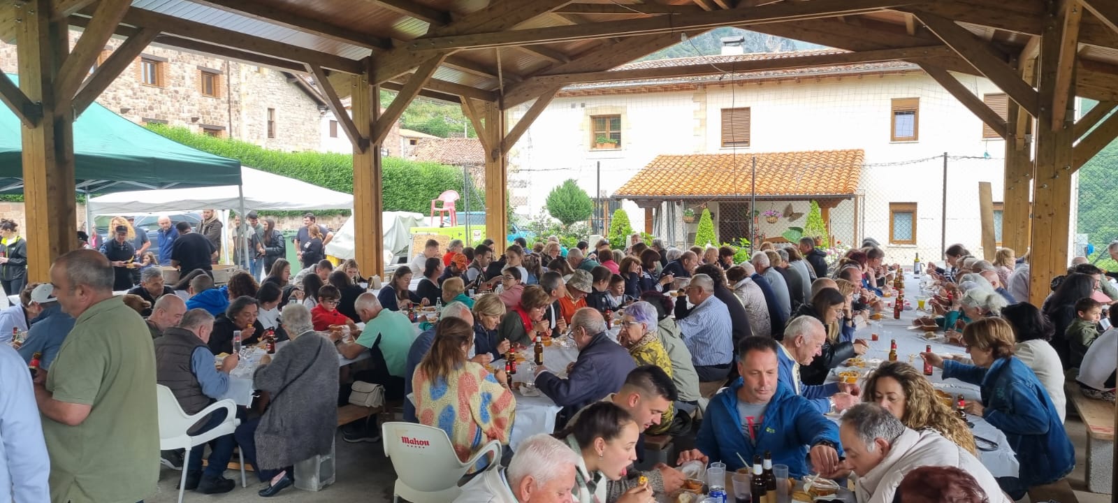 Participantes en la comida popular y solidaria sentados a la mesa en la plaza de Linares