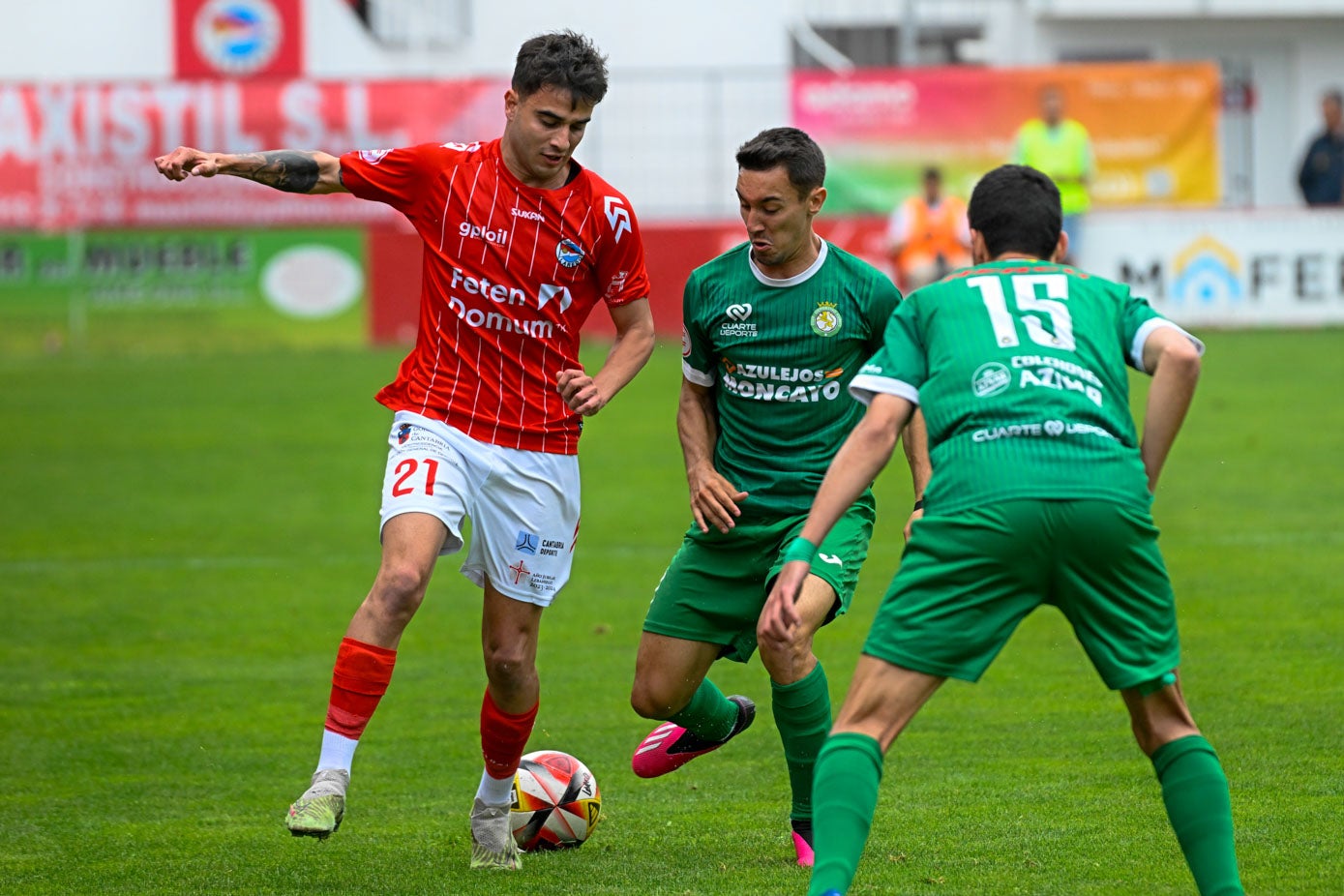 Un jugador del Laredo controla el balón ante dos rivales del Cuarte