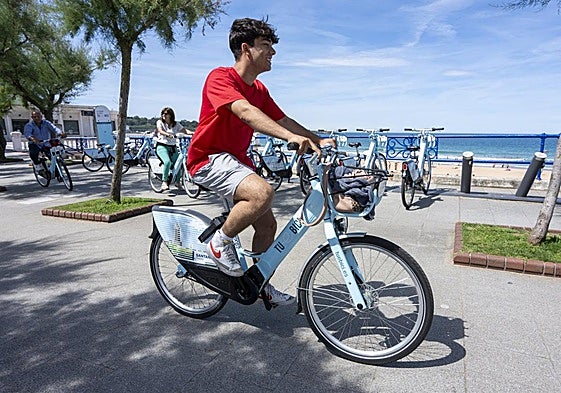 El Sardinero. Un usuario utiliza la bicicleta municipal en la parada de la Plaza de Italia.
