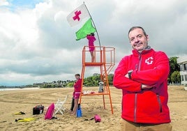 Agustín Salán, en el Sardinero, ante una de las torres de vigilancia con tres jóvenes socorristas.