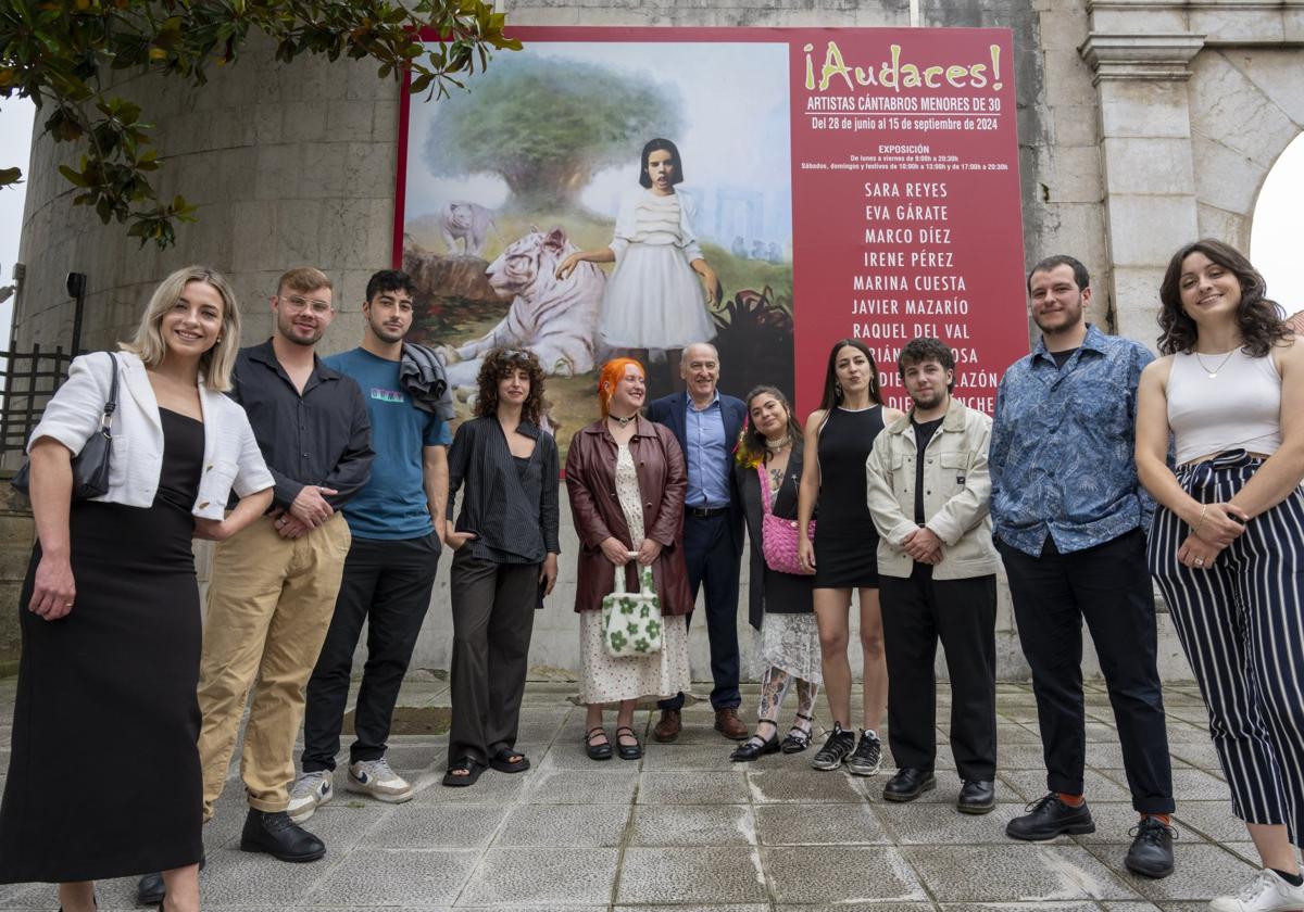 Irene Pérez, Pablo Diego Villazón, Javier Mazarío, Sara Reyes, Eva Gárate, Jesús Alberto Pérez Castaño, Marián Espinosa, Marco Díez, Manuel Diego Sánchez y Marina Cuesta, junto al cartel que anuncia la exposición que permanece en el Parlamento de Cantabria.