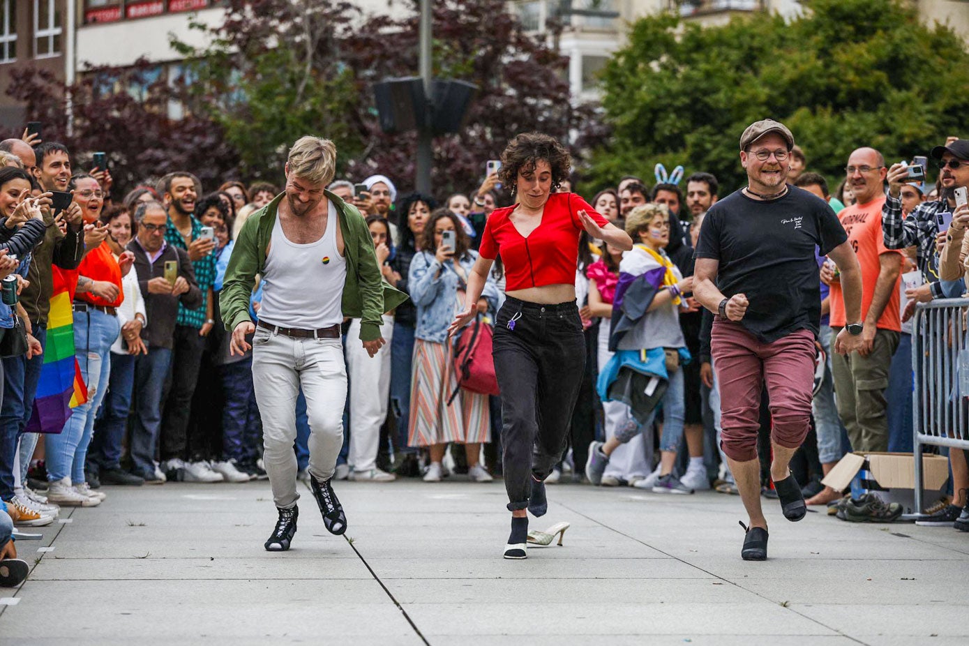 Tres participantes de la carrera de tacones corre ante un público entregado.