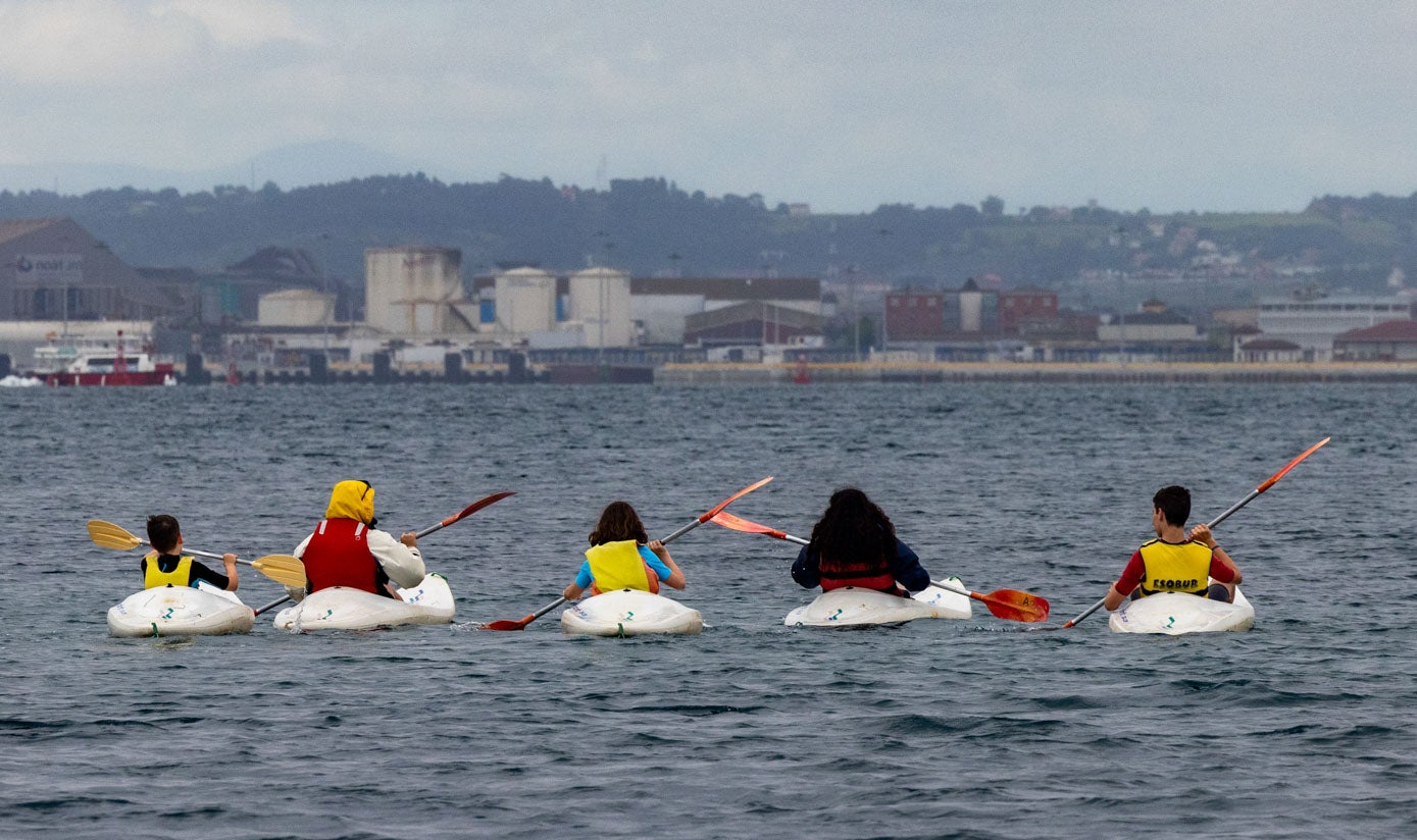 Unos niños cursando su clase de piragüismo por la bahía de Santander.