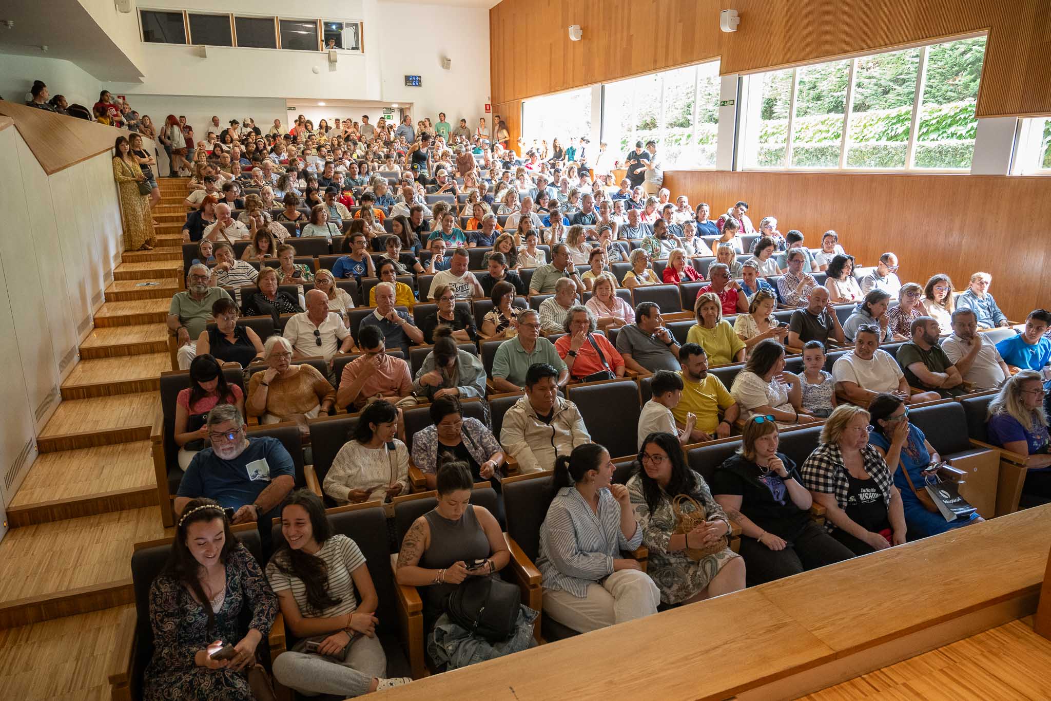 Vista del salón, lleno por completo y con gente de pie al fondo. 