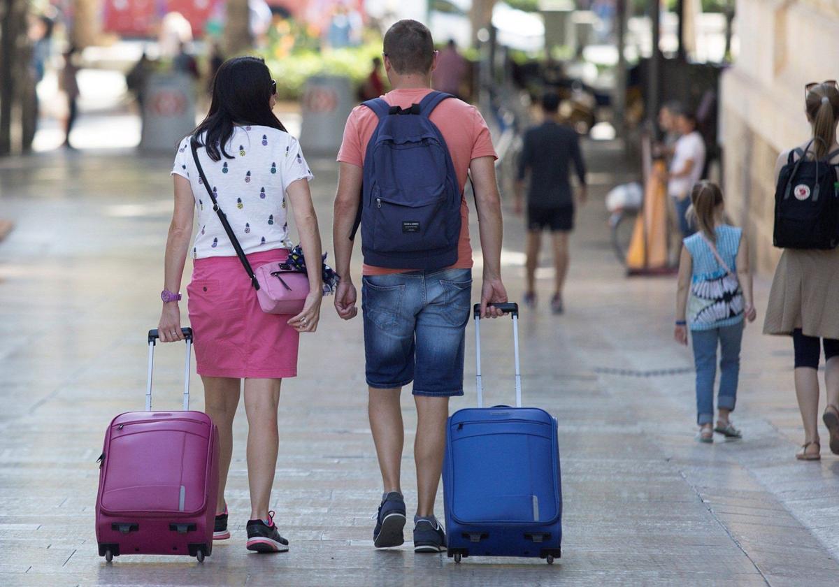 Una pareja de turistas con su equipaje por las calles.