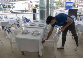 Un camarero prepara una terraza de hostelería en Somo.