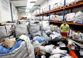 Un operario del servicio de Recogida de Residuos se encarga de apilar nuevos lotes de ropa, en las saturadas instalaciones de este departamento (Barreda).