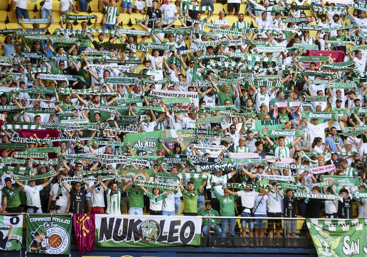 Los aficionados racinguistas, con las bufandas en alto, animan al equipo durante un partido.