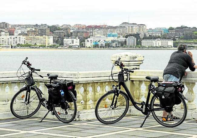 Una pareja aparca sus bicis para observar el mar desde La Magdalena.