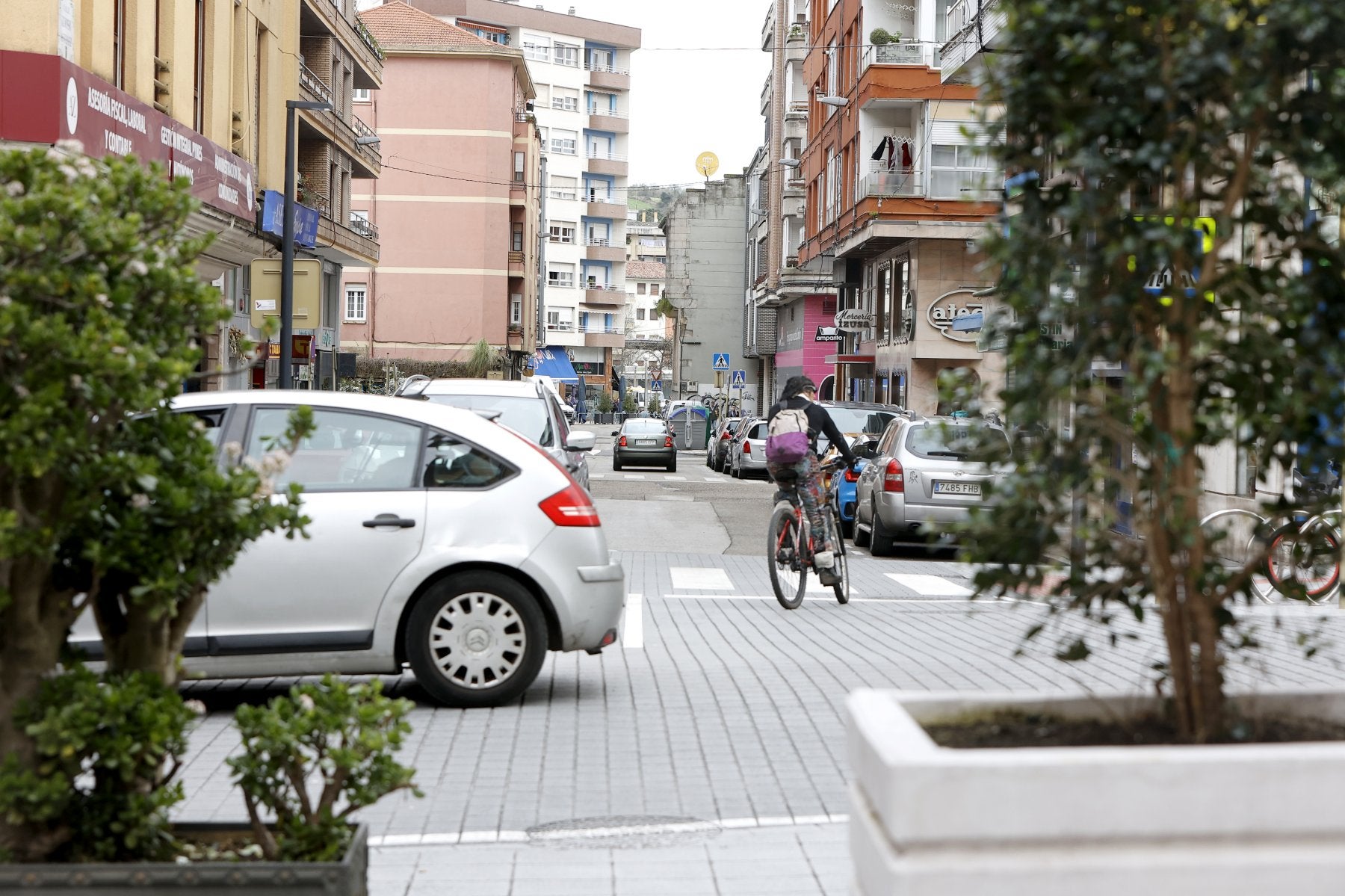 Un coche circula por la calle Julián Ceballos, mientras un ciclista gira hacia la calle Alonso Astúlez, en Torrelavega.