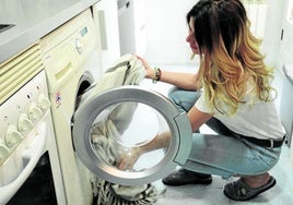 Una mujer prepara una lavadora en su casa.