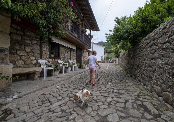 Una niña corre delante de un perro en una calle del pueblo de San Martín de Toranzo.