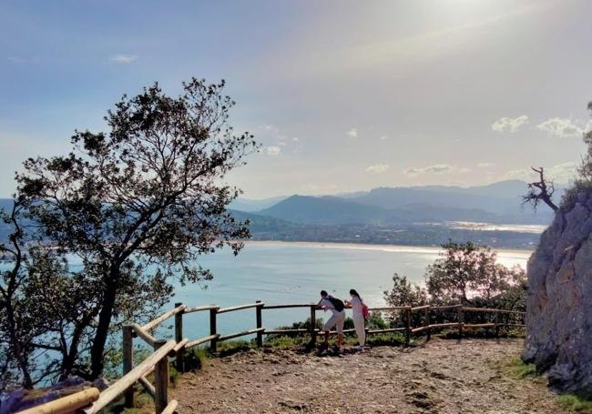 Dos caminantes contemplan la bahía en el mirador junto a la peña El Fraile.