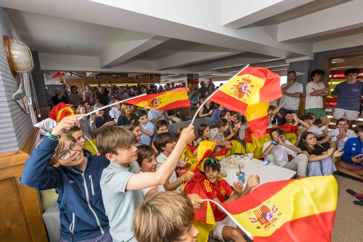 Jóvenes del Marítimo celebrando la victoria de su favorito, Diego Botín. El cántabro ha conseguido la primera medalla de oro para España.