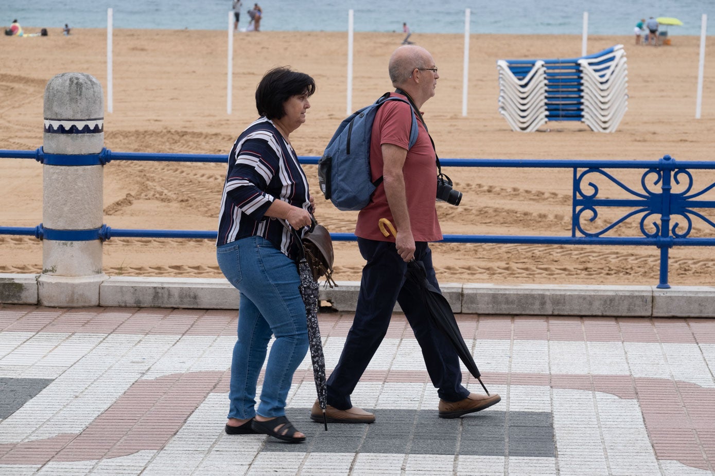 Una pareja pasea por el borde de la playa, en El Sardinero, cámara en ristre