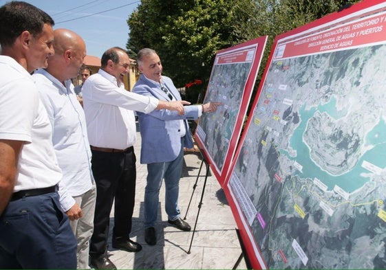 El consejero y los alcaldes observan los planos del proyecto.