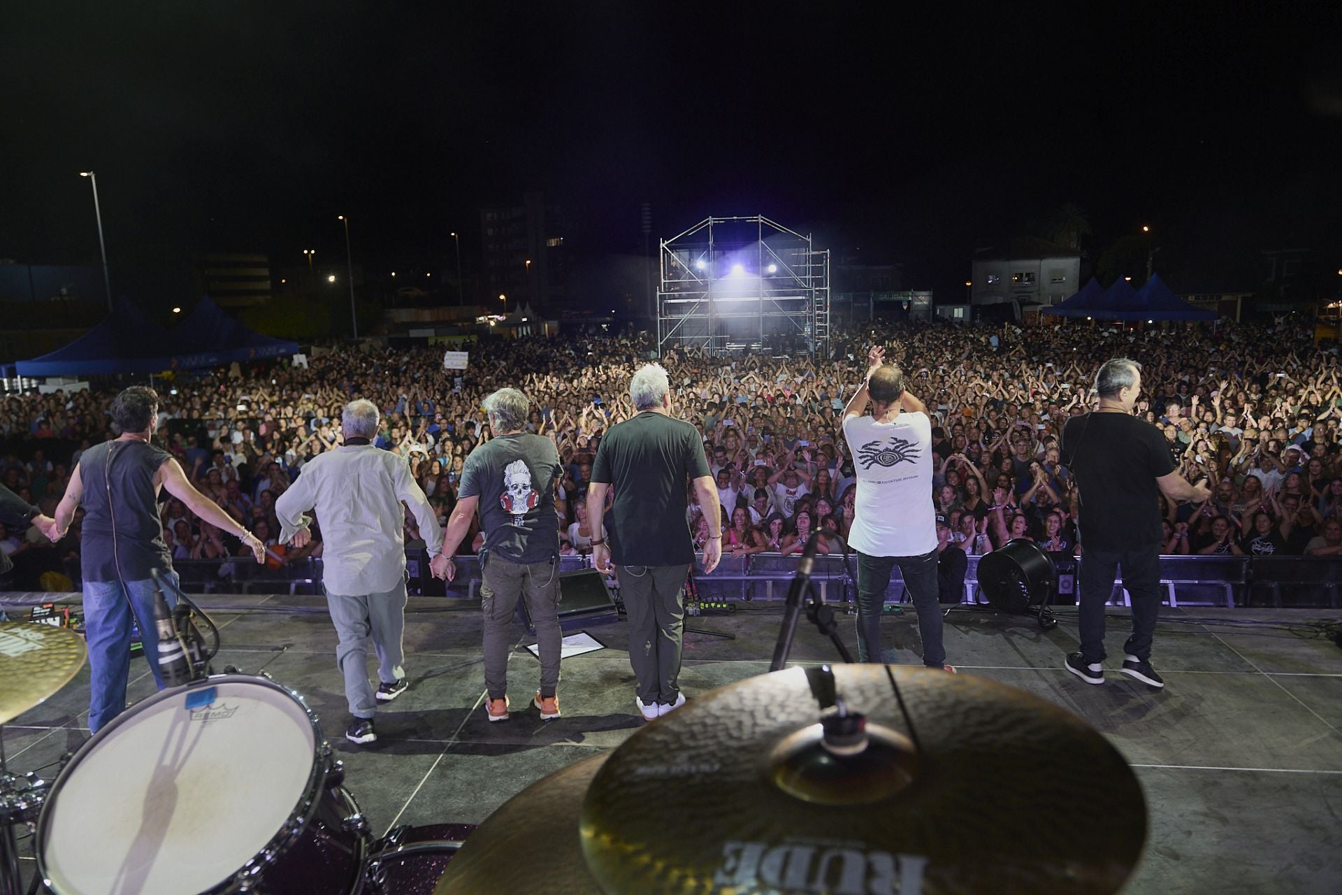 Los miembros de Hombres G saludan al público que les aplaude con los brazos en alto