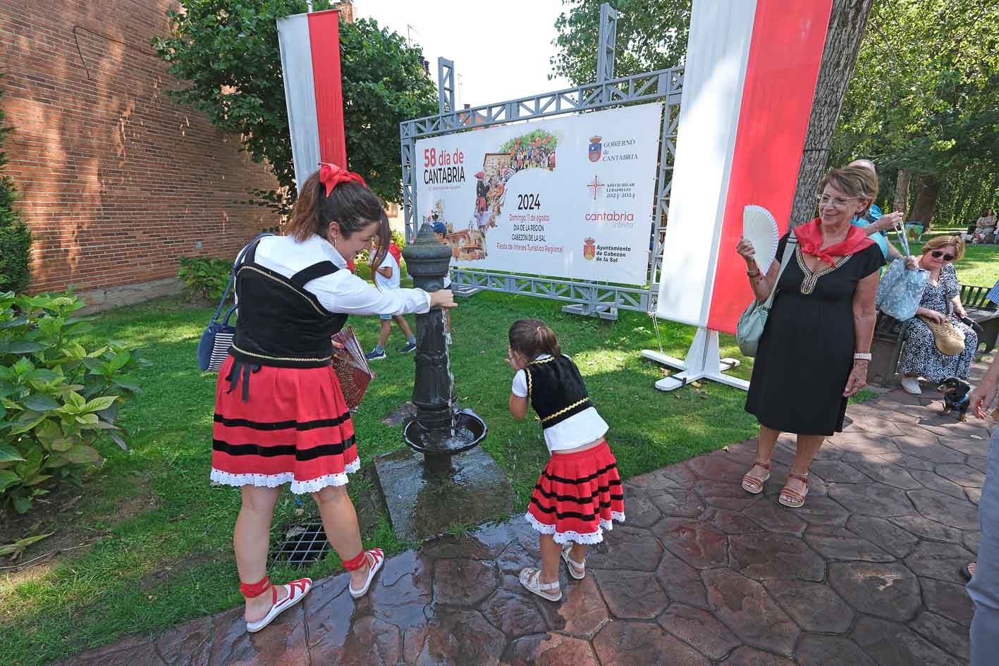 Dos niñas se refrescan en una fuente.