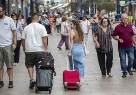 Dos turistas caminan con sus maletas por la calle Burgos, en Santander.