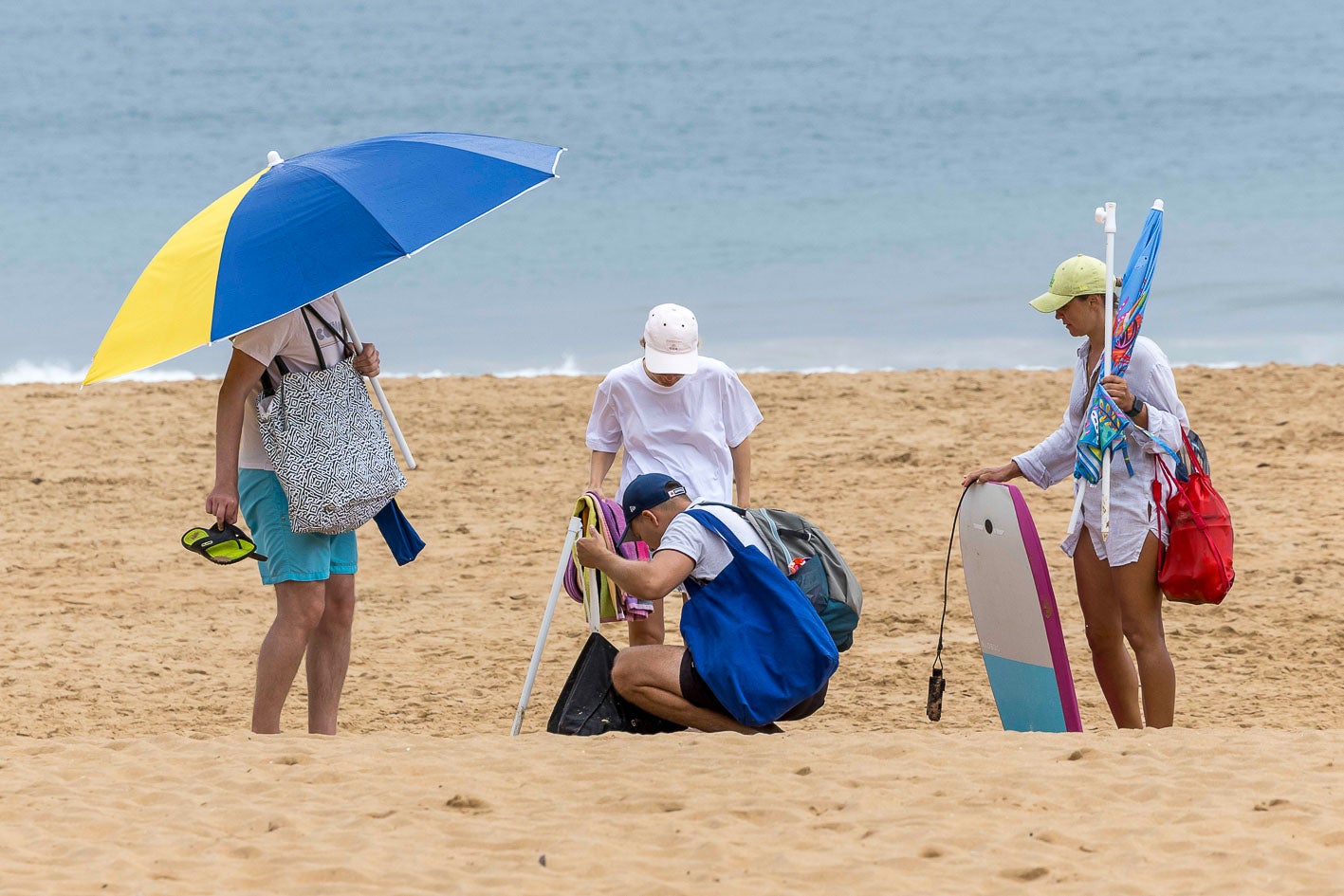 Los bañistas se protegen de la lluvia con la sombrilla que hasta ese momento les servía para evitar el sol.