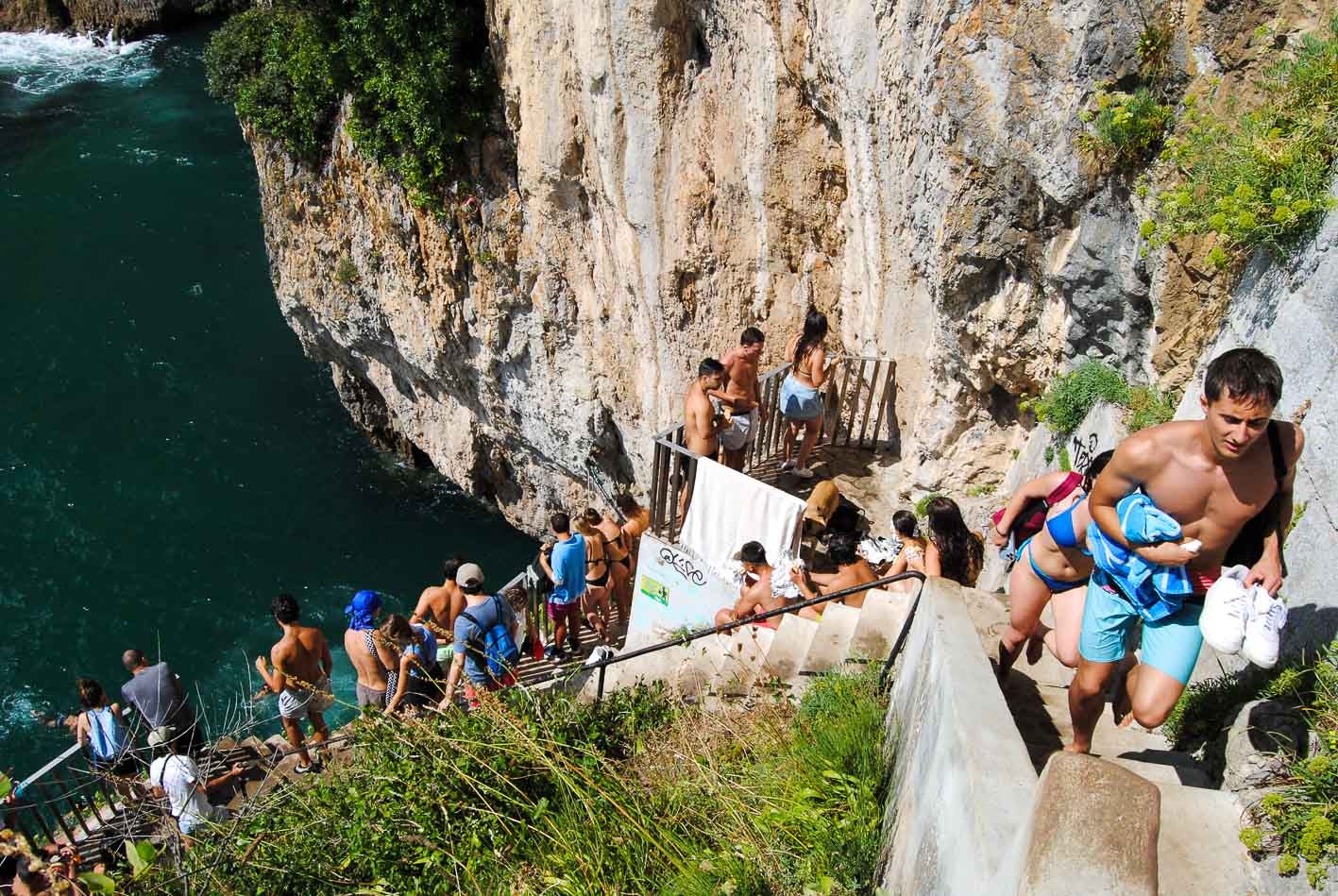 Los más jóvenes se concentran en los escalones que acaban en el mar y aprovechan para tirarse al agua. 