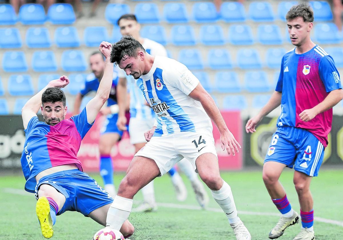 Dani Gómez, de la Gimnástica, trata de proteger el balón ante un rival del Langreo