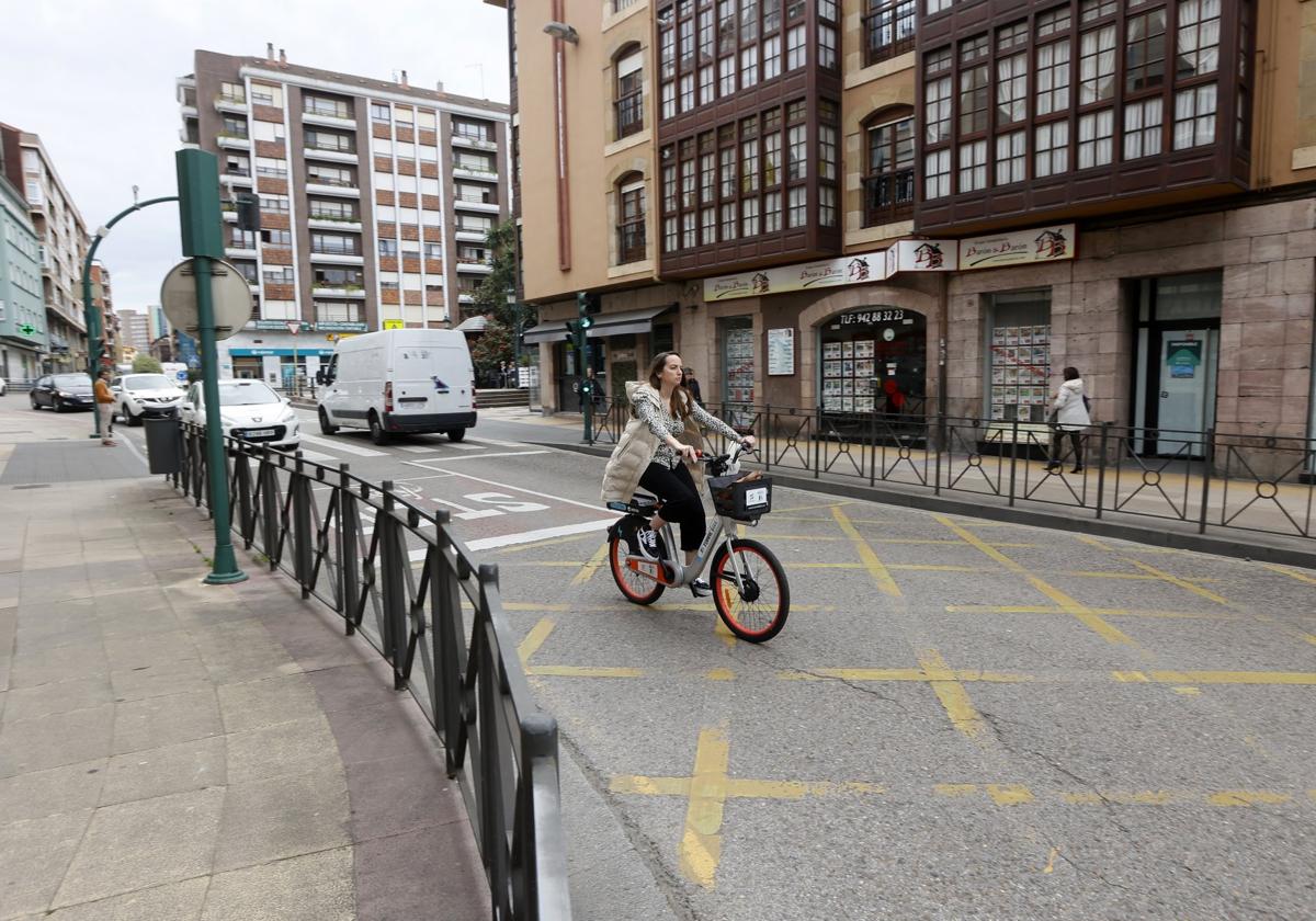 Una joven circula con una bicicleta eléctrica por Torrelavega en la zona de Cuatro Caminos.