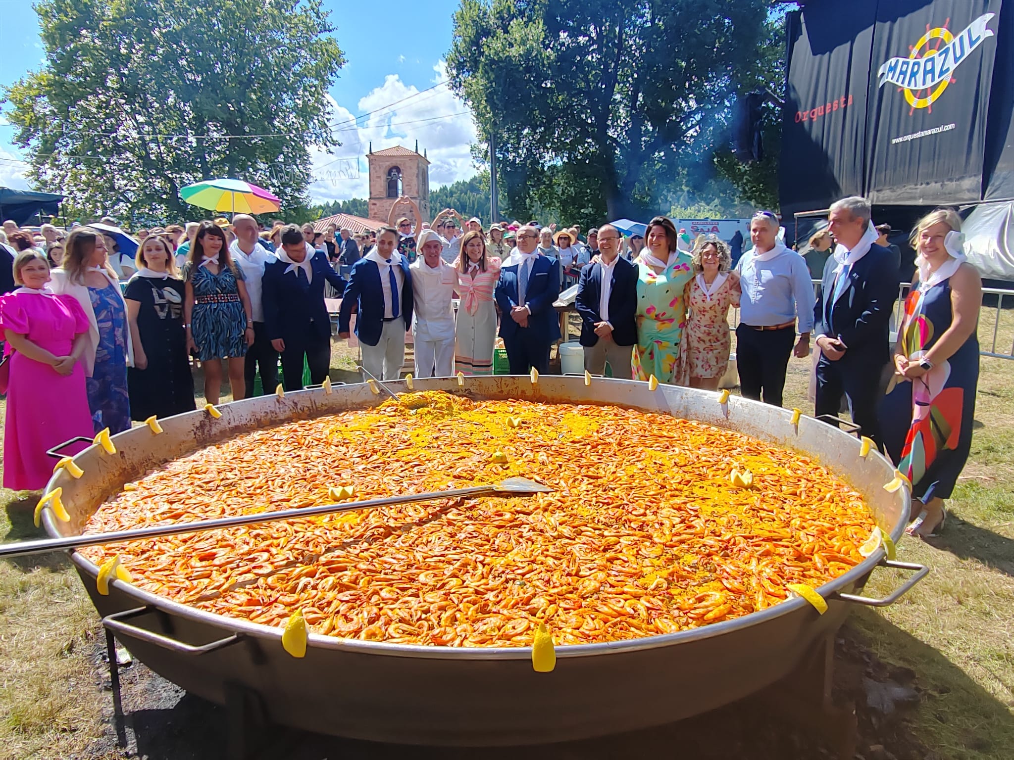 Las autoridades locales y regionales posan con la paella ya lista para repartir a los vecinos.