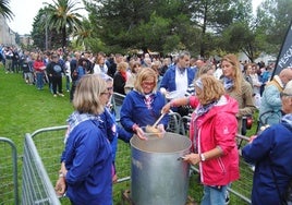 Las mujeres de Cantabria en Rosa sirven el marmite a los vecinos que aguardan en las filas. .