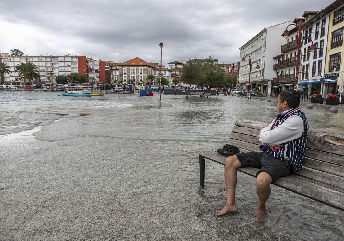 Un hombre observa sentado la inundación provocada, en octubre del año pasado, por la alta pleamar en San Vicente de la Barquera.