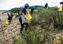 Voluntarios de la convocatoria de Telefónica retiran en bolsas los residuos que se encuentran a su paso por las dunas de Somo.