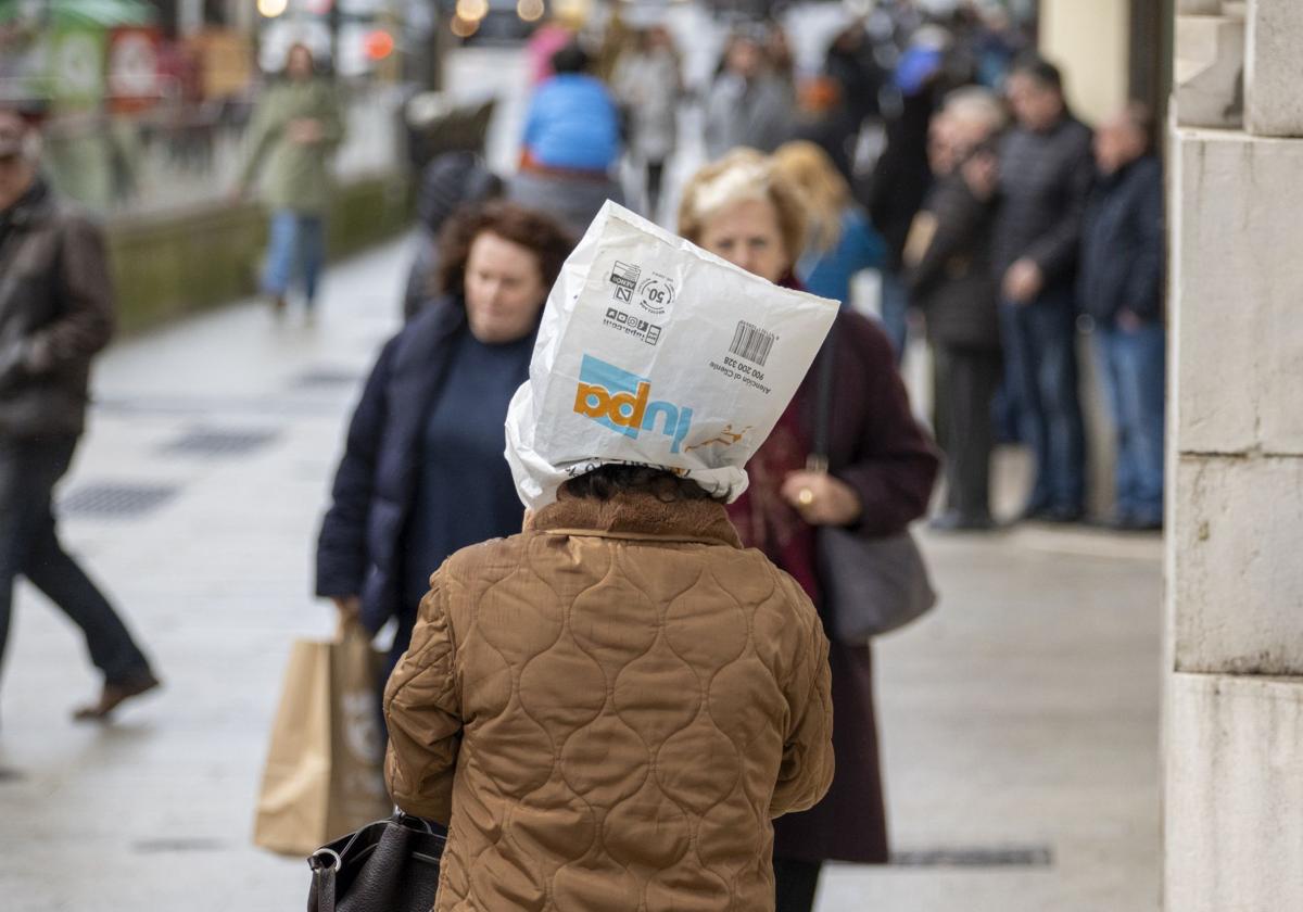 Una mujer se cubre la cabeza con una bolsa para protegerse del viento.