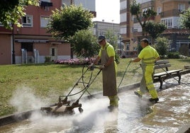 Dos trabajadores limpian el pavimento en una plaza del barrio Nueva Ciudad.