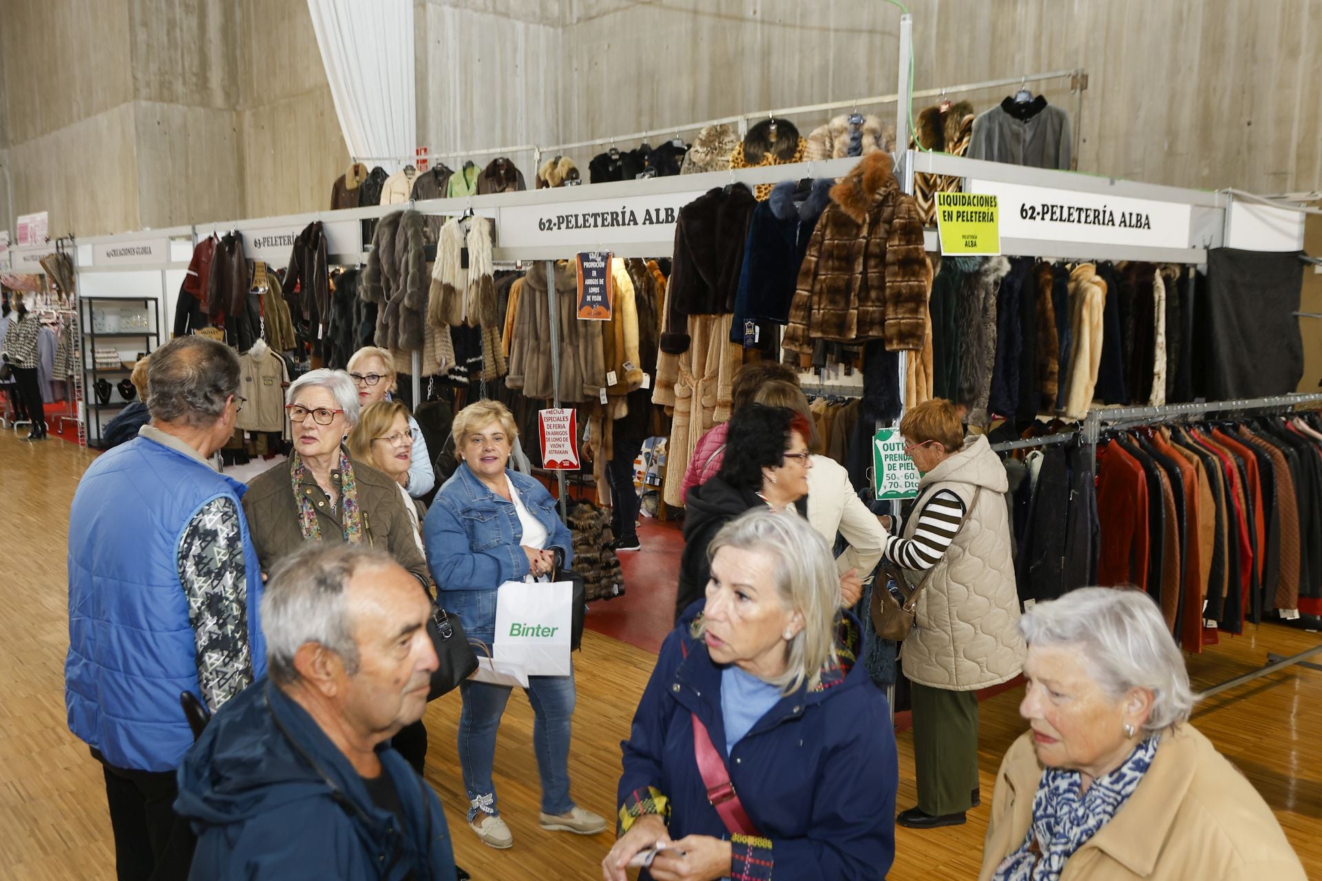 Visitantes de la feria frente a un stand de una tienda de peletería. 