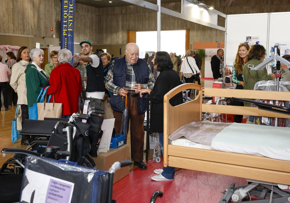 Asistentes a la feria junto a uno de los stands con camas ortopédicas en venta.