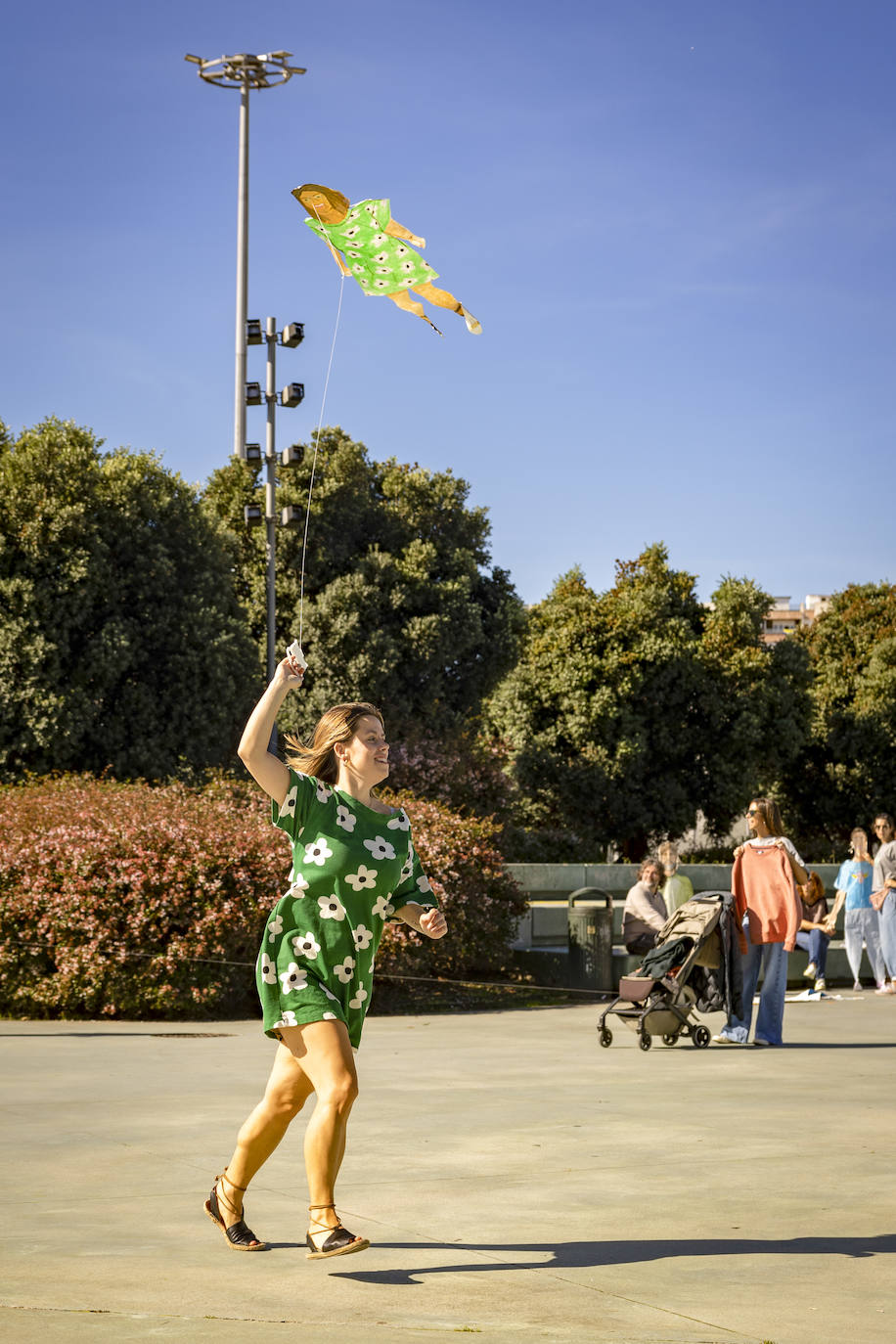 Llamativa cometa con vestido verde de flores, igual al que lleva la joven