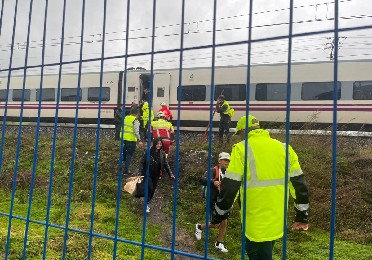 Imagen principal - Los bomberos y la Guardia Civil han ayudado a bajar del tren a los pasajeros para llegar hasta Aguilar en autobús. 