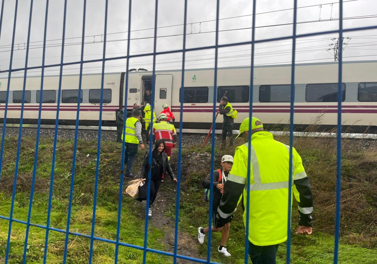 Los pasajeros del Alvia que partió a primera hora de Santander, ayudados por los bomberos y la policía para deslojar el convoy.